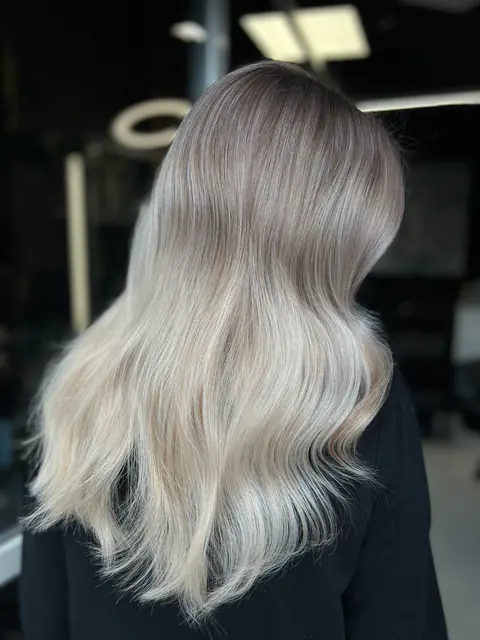 Păr lung cu rădăcina cenușie care se topește treptat în blond glacial, ondulat lejer