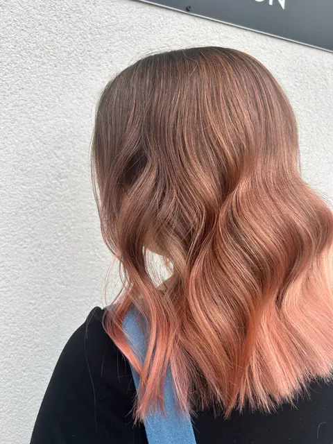 Lob cu ombré de la castaniu la rose gold și valuri lejere, fotografiat în fața salonului
