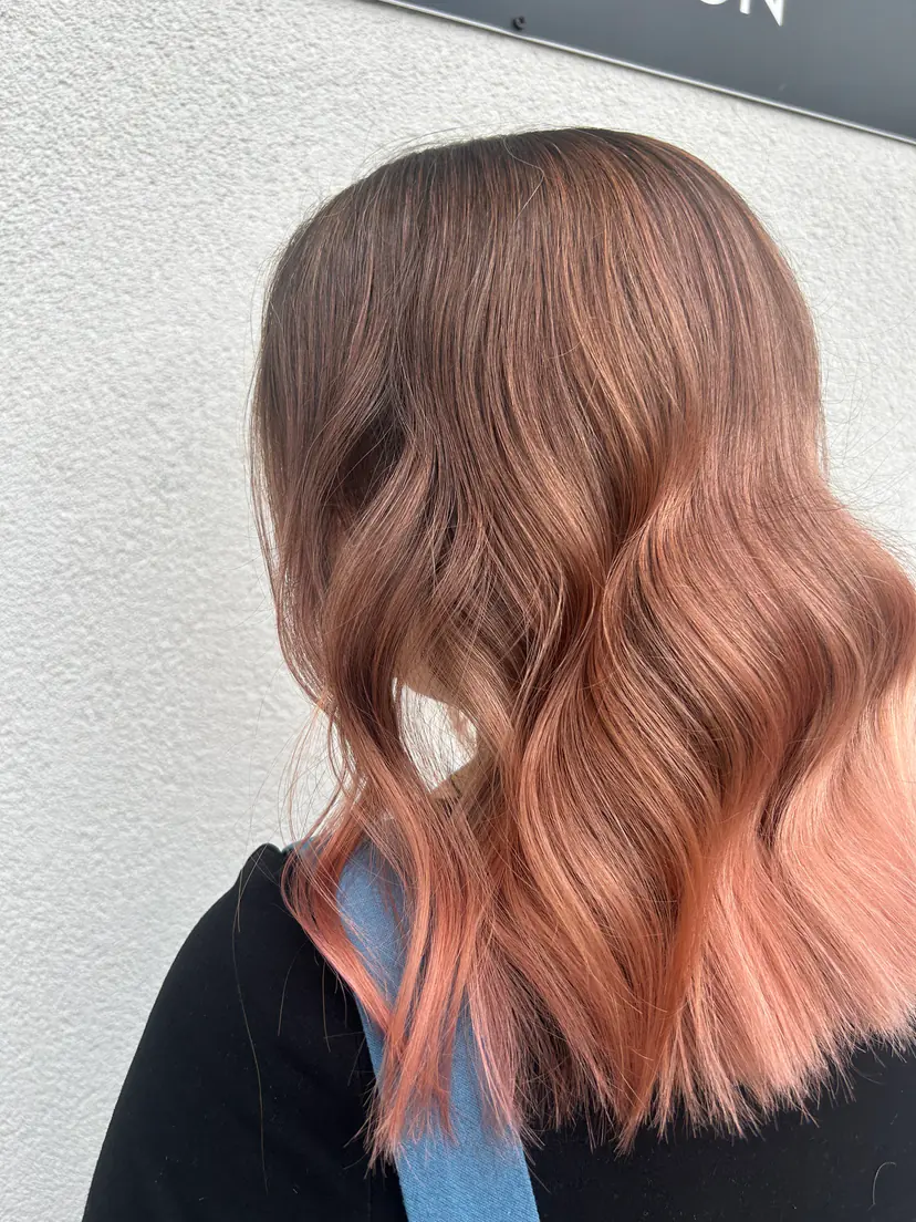 Lob cu ombré de la castaniu la rose gold și valuri lejere, fotografiat în fața salonului