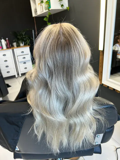 Balayage blond argintiu cu valuri, fotografiat pe scaunul de coafor