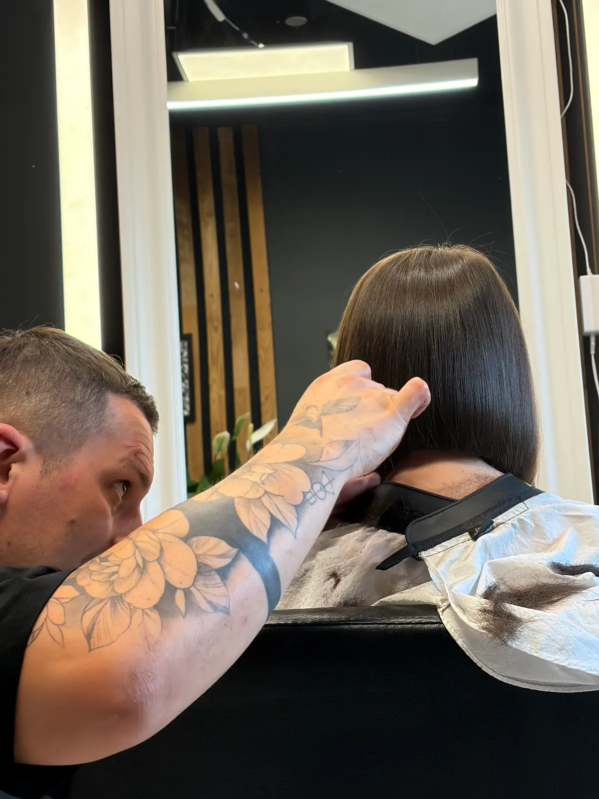 Attila verifică simetria unui bob în oglinda salonului, înainte de ultimele tăieturi